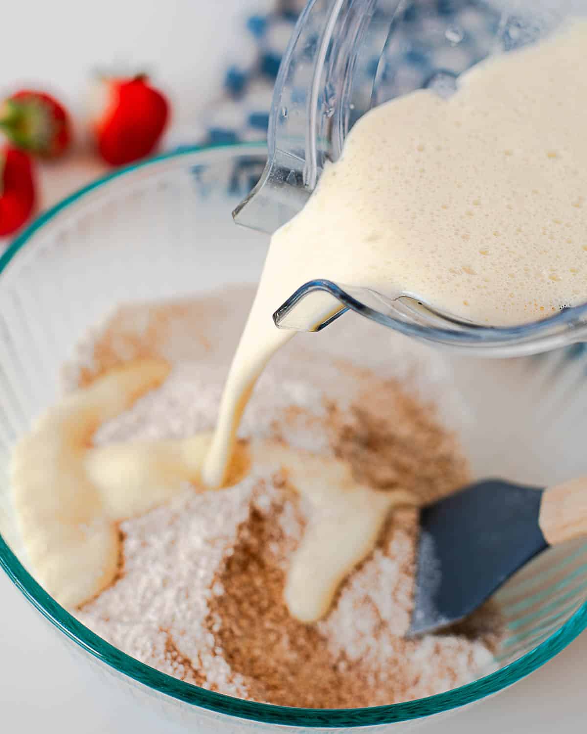 Wet ingredients being poured into dry ingredients to make strawberry coffee cake batter