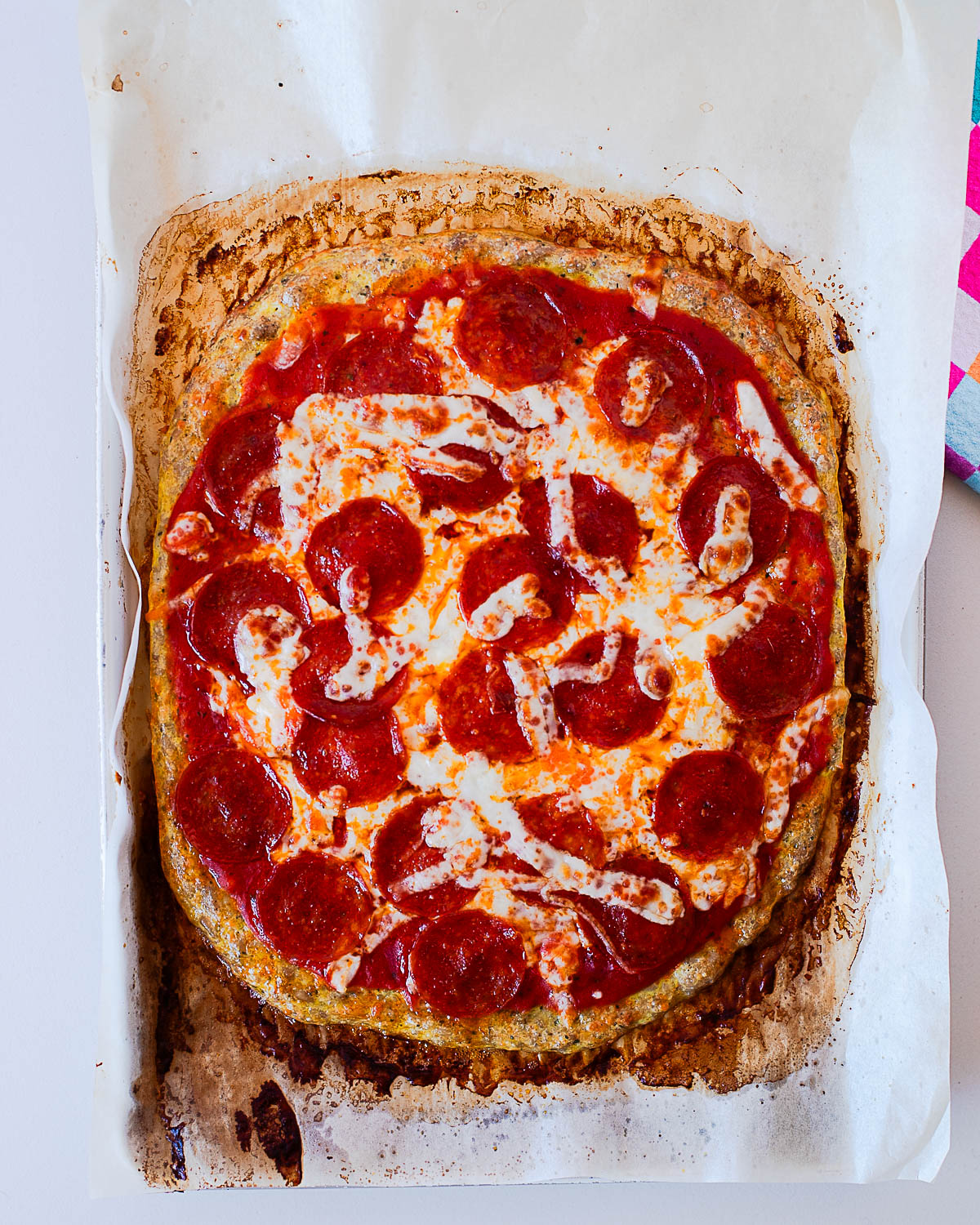 Baked pepperoni chicken crust pizza with melted mozzarella and crispy pepperoni slices on parchment paper.