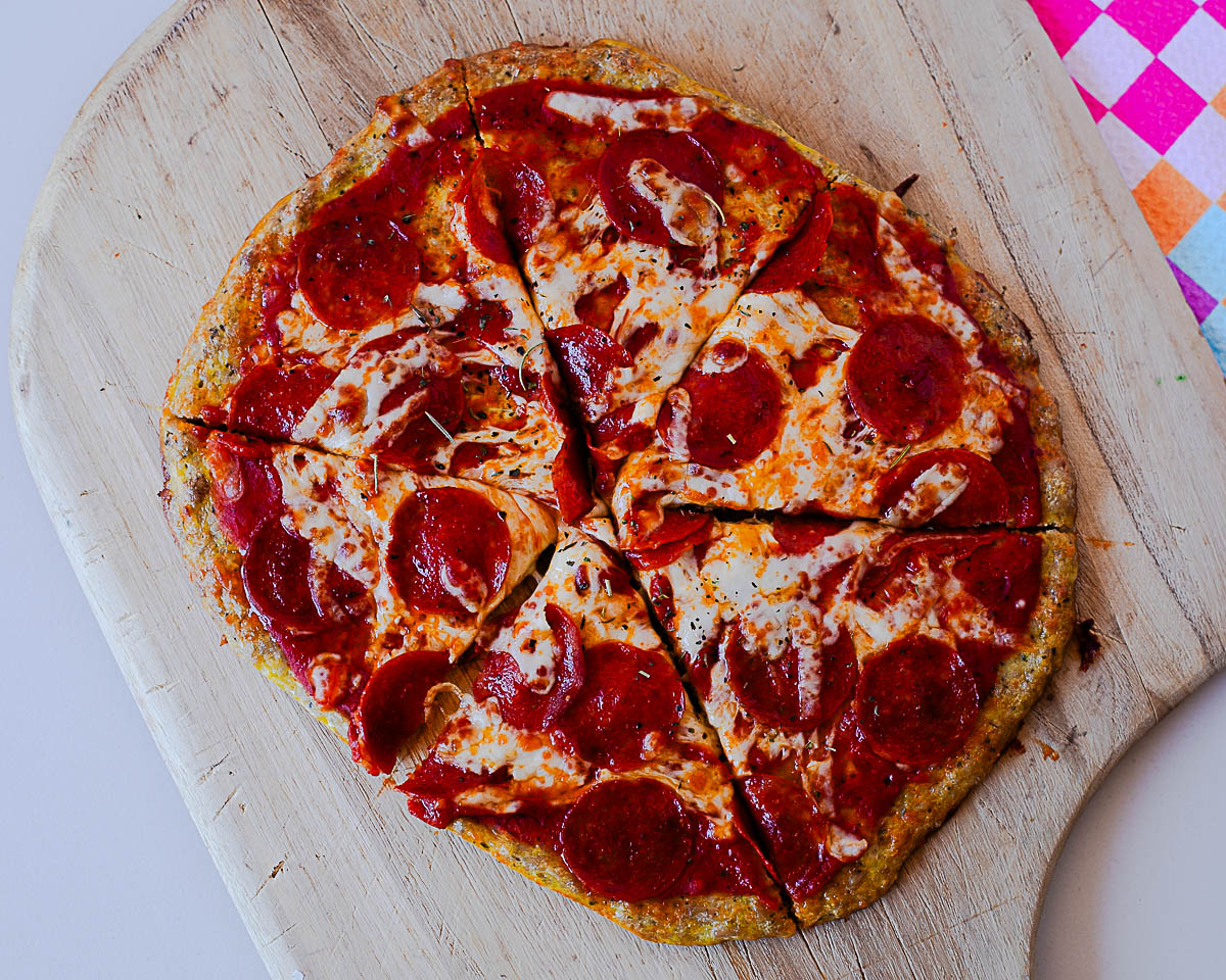 Pepperoni chicken crust pizza slice with melted cheese and crispy pepperoni in focus.