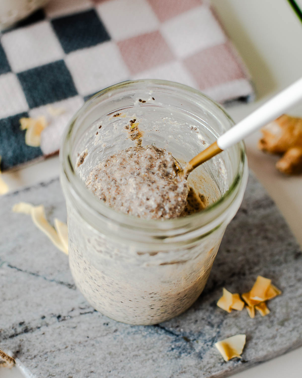 Spoonful of high protein coconut chia pudding lifted from a mason jar, showing the thick creamy texture with chia seeds throughout and a Greek yogurt topping.