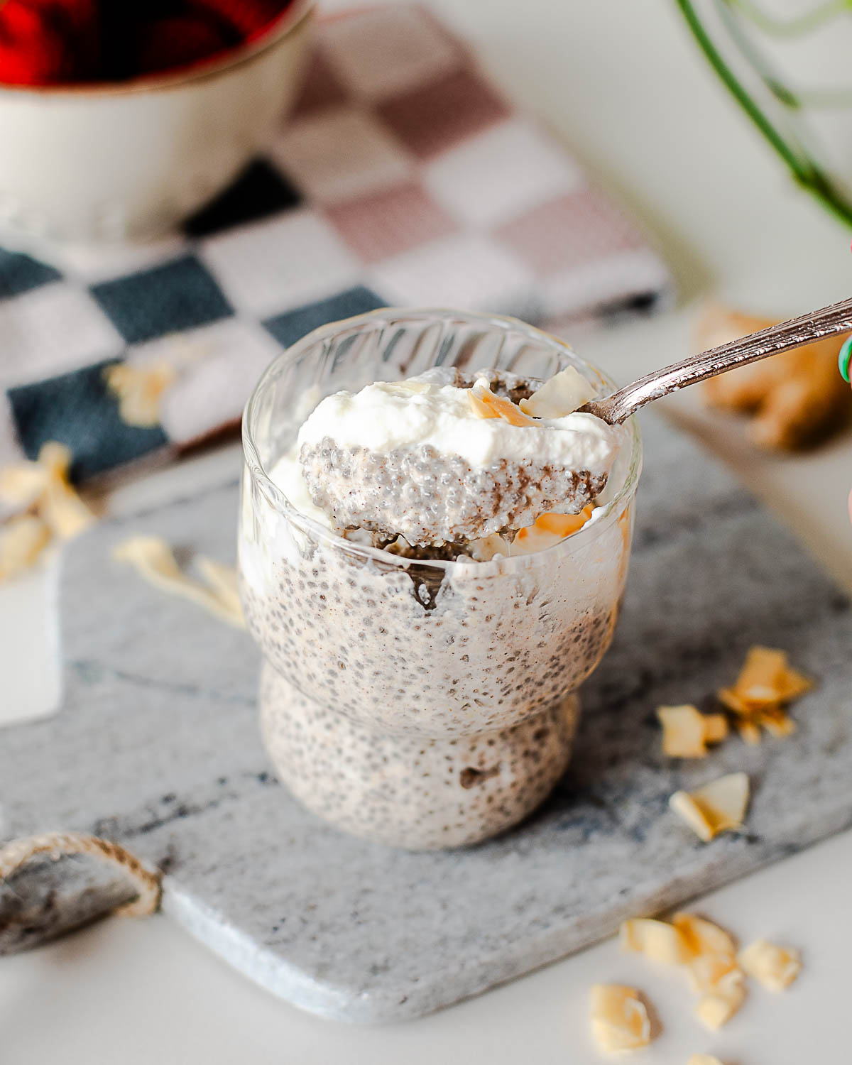 Close-up of creamy coconut chia pudding topped with Greek yogurt and toasted coconut flakes with a spoon scooping into the pudding.