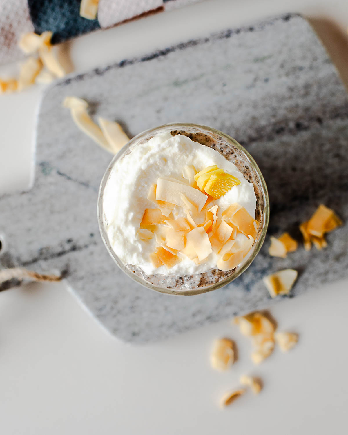 Overhead view of coconut chia pudding topped with Greek yogurt and toasted coconut flakes on a marble serving board.