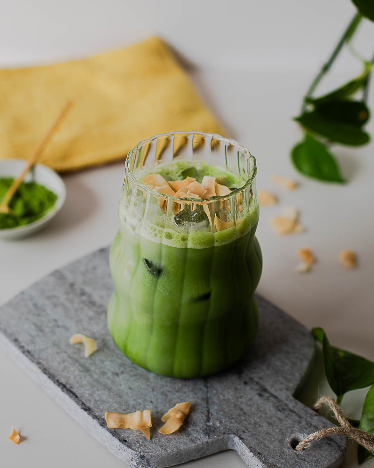 Coconut matcha latte with toasted coconut topping and layered green matcha tea in a glass over ice.