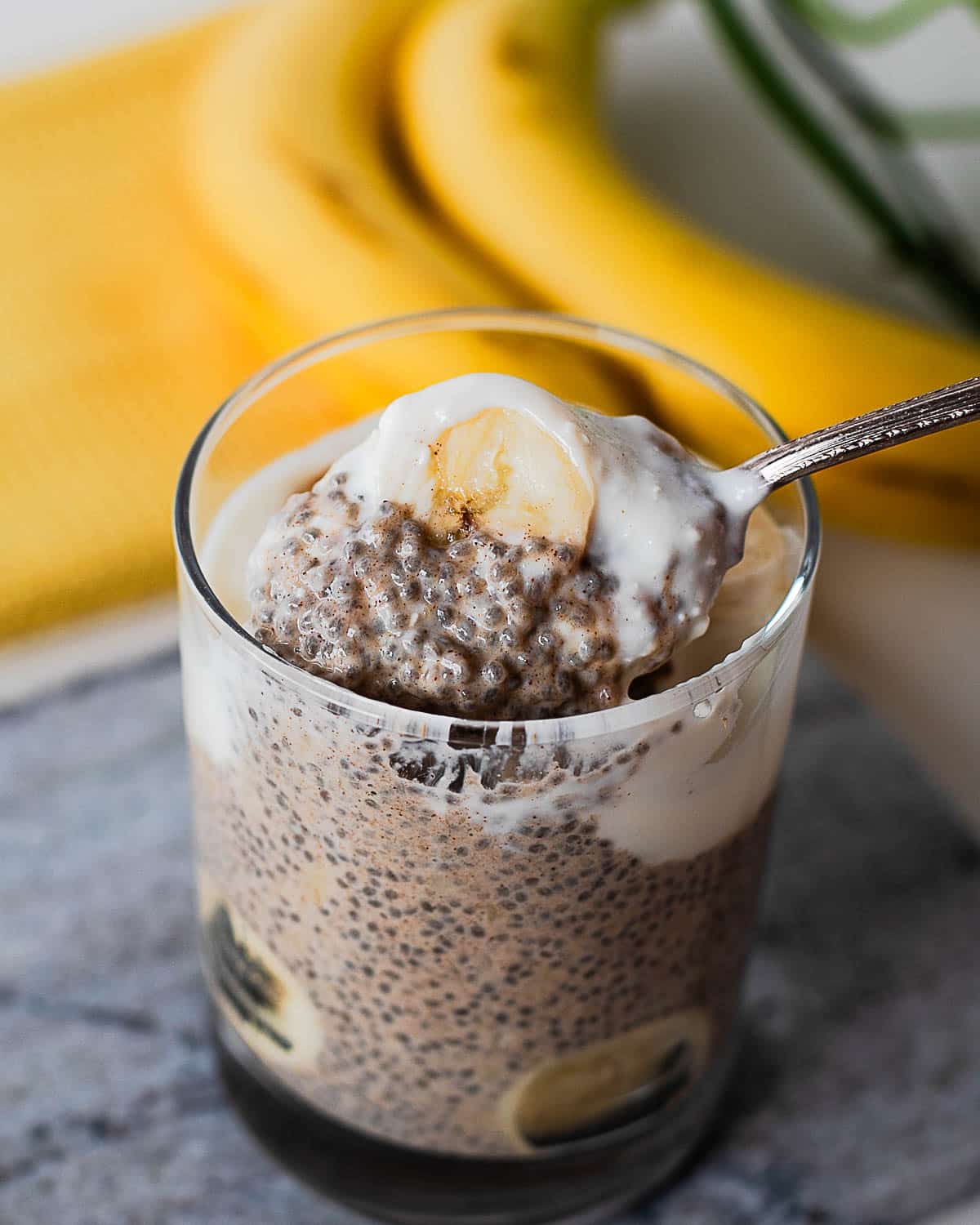 Spoonful of banana chia pudding with creamy yogurt topping and fresh banana slices, showcasing the thick and satisfying texture.
