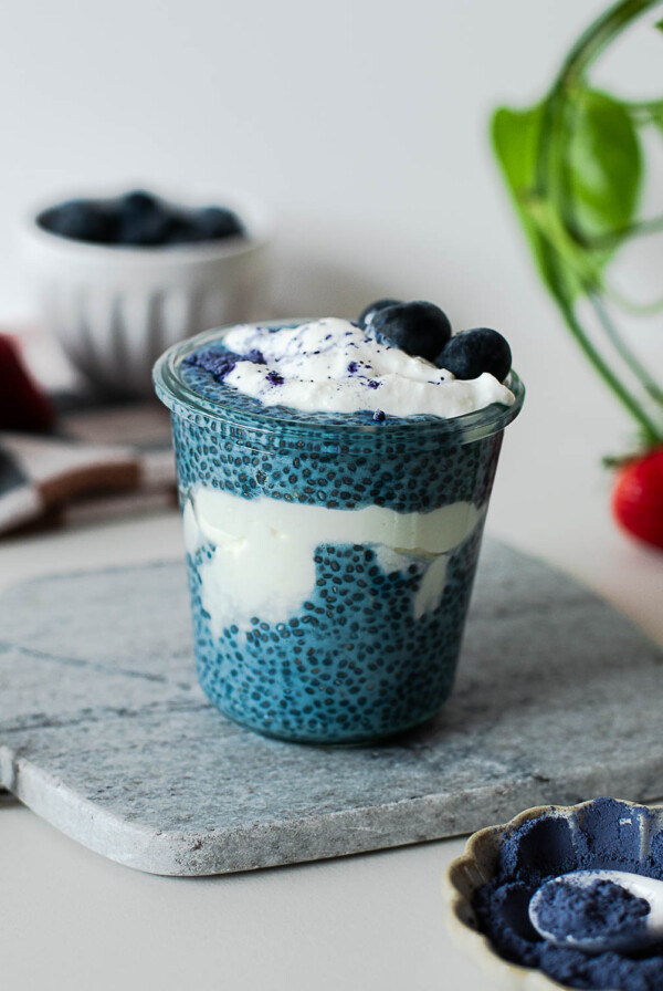 High-protein blue chia pudding layered with Greek yogurt and topped with fresh blueberries and butterfly pea powder.