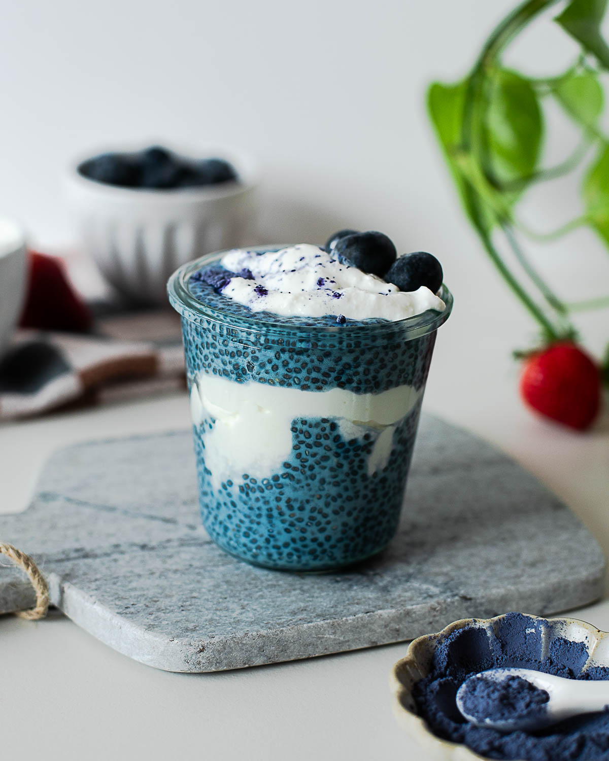High-protein blue chia pudding layered with Greek yogurt and topped with fresh blueberries and butterfly pea powder.