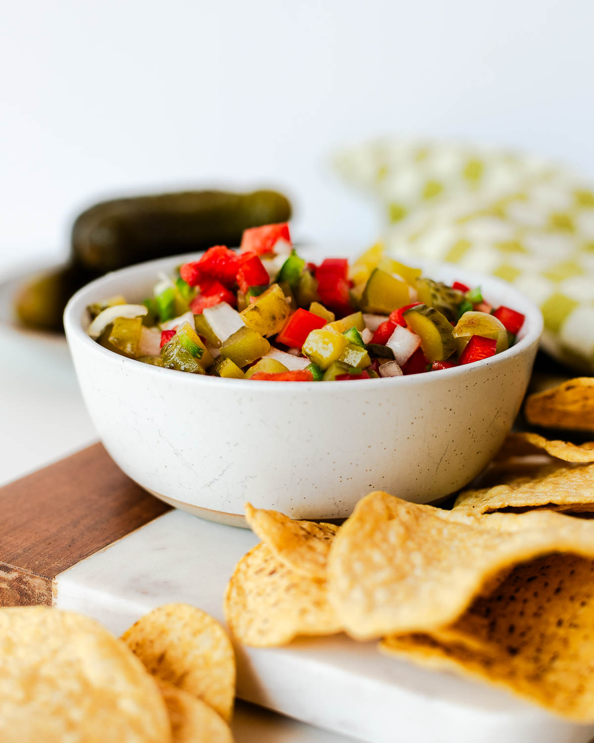 Side view of a bowl of pickle de gallo with tortilla chips, highlighting the chunky texture and vibrant colors of this fresh pickle salsa.