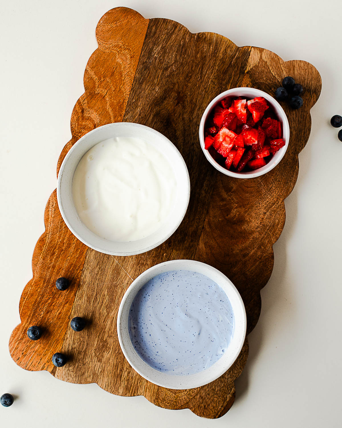 Prepped and ready smooth vanilla whipped cottage cheese and naturally blue butterfly pea flower cottage cheese with diced strawberries, ready to assemble into patriotic parfaits.