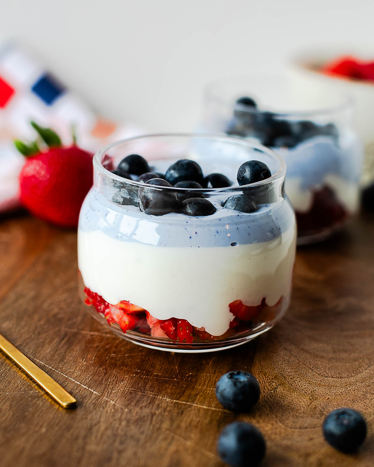 Red, white, and blue cottage cheese parfait layered with fresh strawberries, whipped vanilla cottage cheese, blue cottage cheese, and blueberries in a glass jar.
