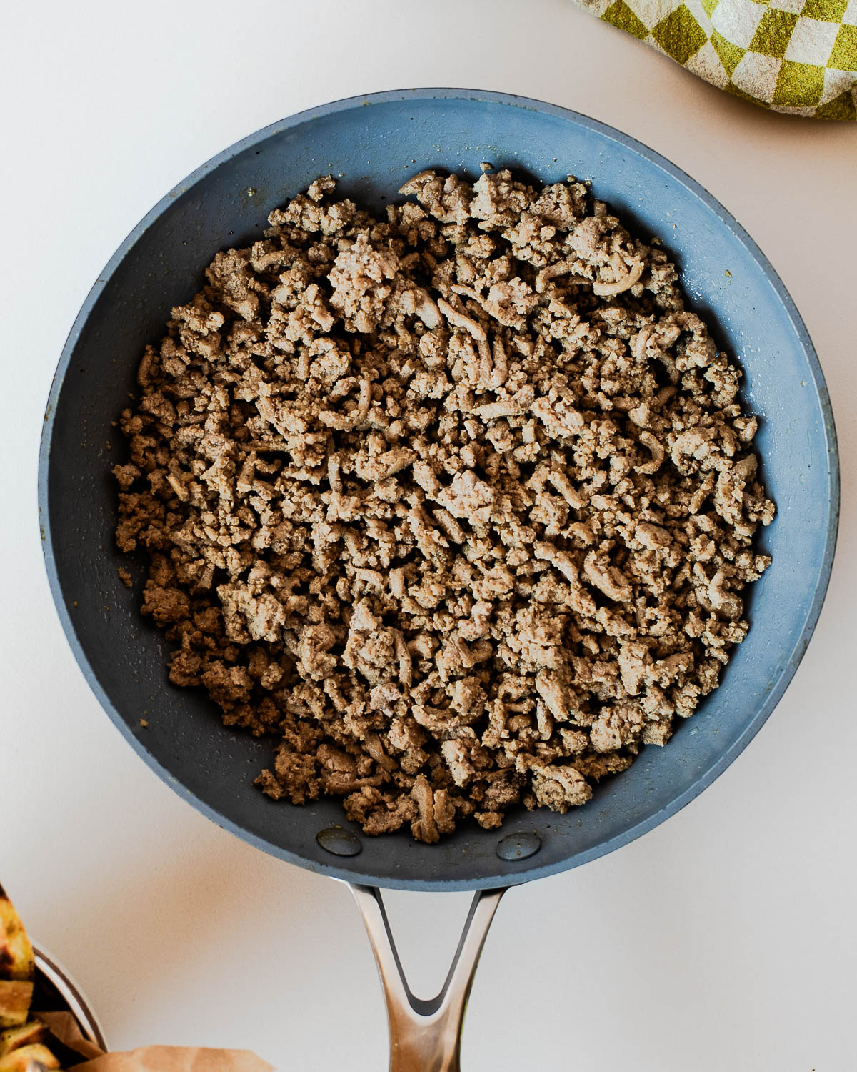 Cooked lean ground turkey crumbled in a large skillet, seasoned and ready for assembling healthy turkey burger bowls.