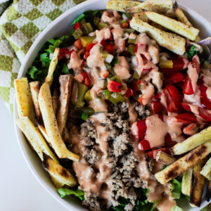 Healthy turkey burger bowl recipe made with seasoned ground turkey, fresh vegetables, homemade burger sauce, and oven-baked sweet potato fries.