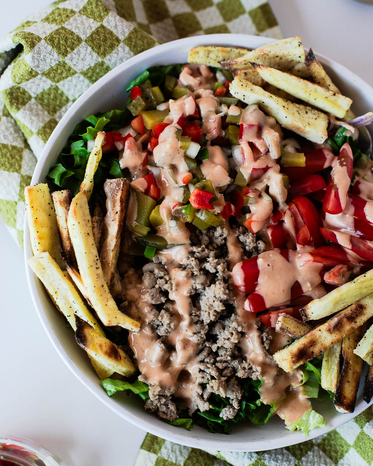 Healthy turkey burger bowl recipe made with seasoned ground turkey, fresh vegetables, homemade burger sauce, and oven-baked sweet potato fries.