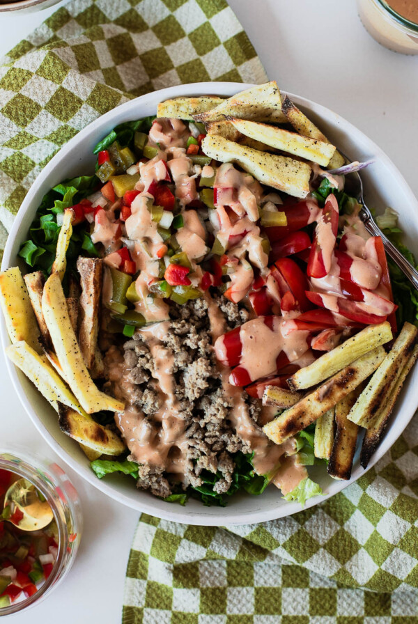 Turkey burger salad bowl with crispy sweet potato fries, pickle de gallo, grape tomatoes, lean ground turkey, and creamy special sauce.