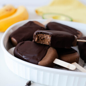 Creamy chocolate avocado popsicles with dark chocolate coating and a bite taken out.