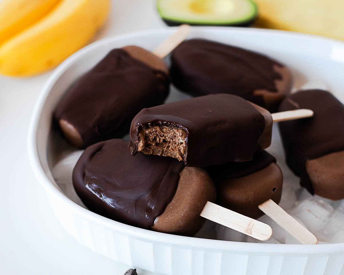 Chocolate-dipped avocado popsicles with a creamy fudgy center.