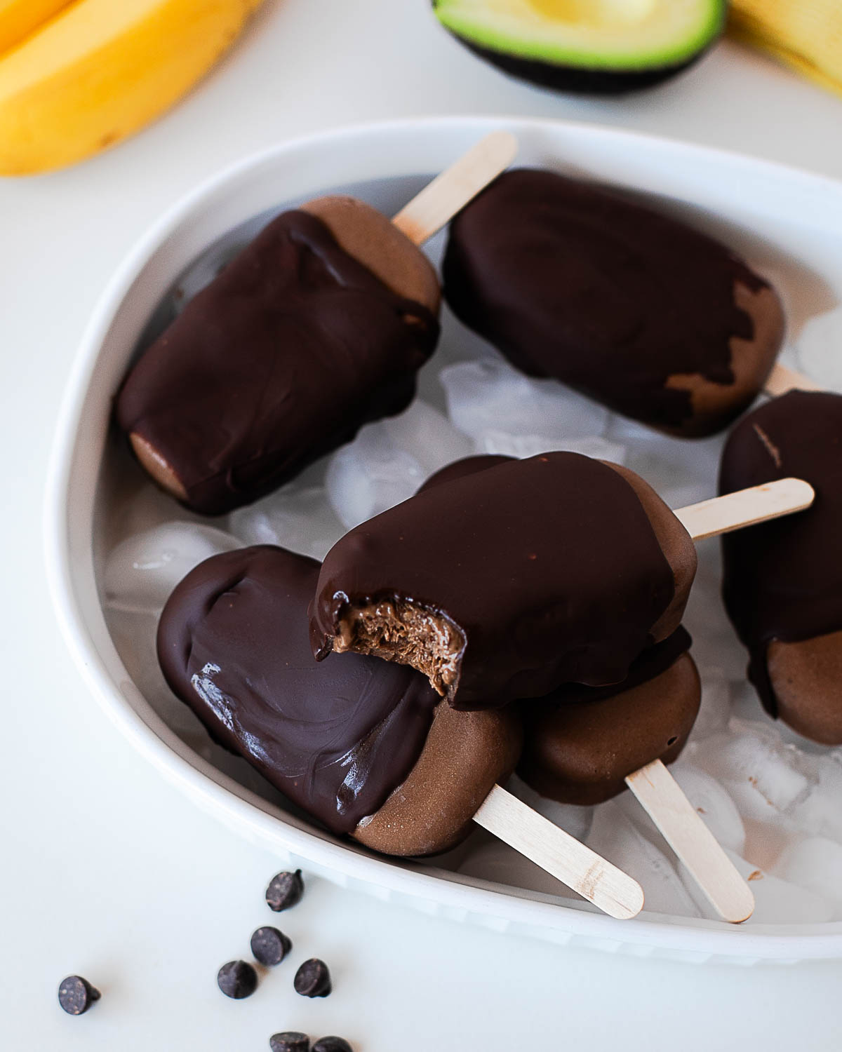 Homemade chocolate avocado fudge pops dipped in dark chocolate and served over ice.