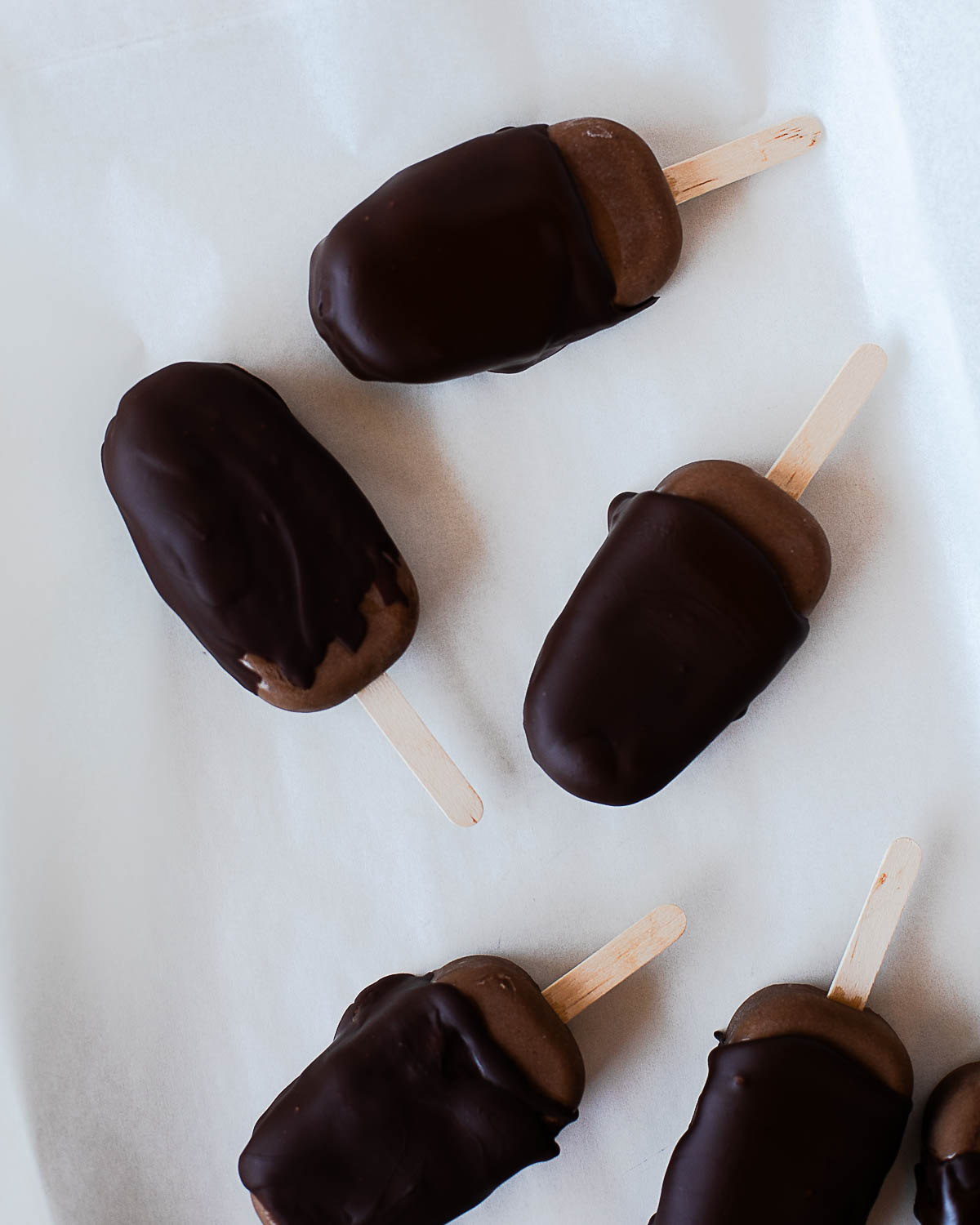 Chocolate avocado protein popsicles partially dipped in melted dark chocolate.