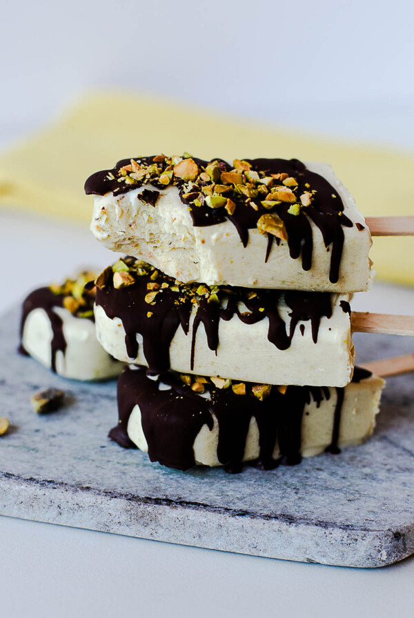 Stacked pistachio protein popsicles with a dark chocolate drizzle and crunchy pistachio topping.