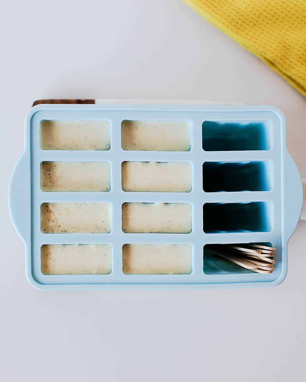 Pistachio popsicle mixture poured into a blue silicone popsicle mold before freezing.