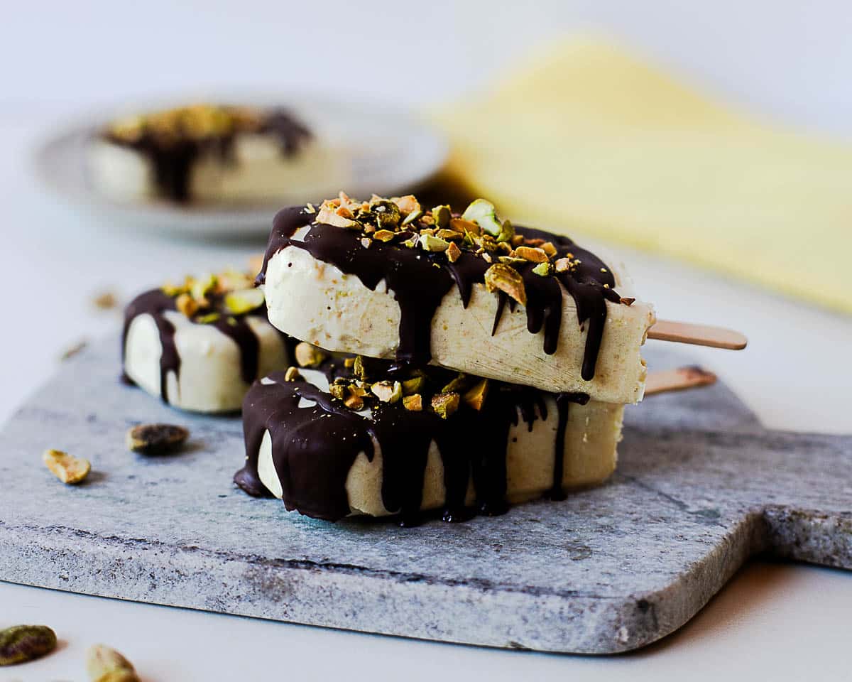 Homemade pistachio popsicles made with coconut milk and cottage cheese, topped with dark chocolate.
