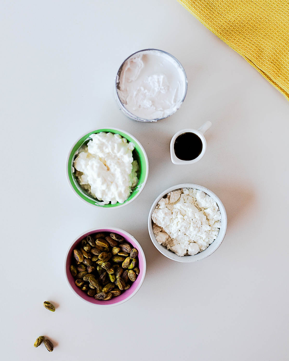 Ingredients for pistachio popsicles including pistachios, cottage cheese, coconut milk, protein powder, and maple syrup.
