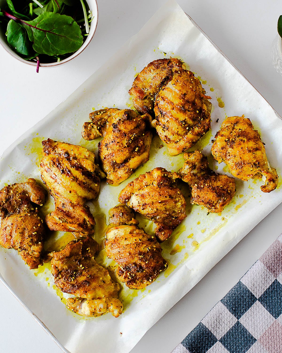 Cooked za’atar chicken thighs resting on parchment paper after being seared and finished in the oven.