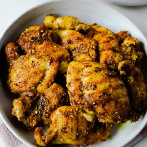 Golden za’atar chicken thighs served in a bowl, seasoned with turmeric, sesame seeds, and herbs.