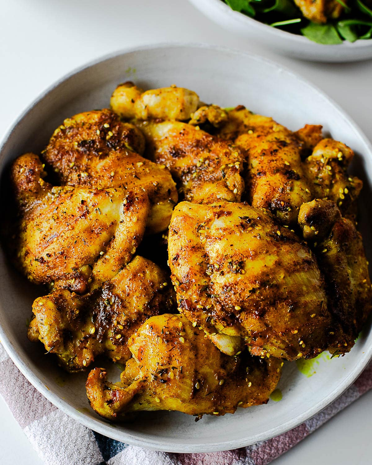 Golden za’atar chicken thighs served in a bowl, seasoned with turmeric, sesame seeds, and herbs.