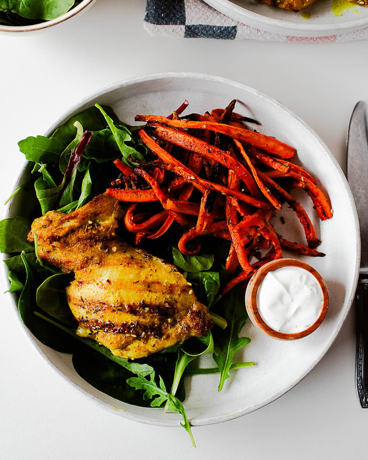 Za’atar chicken thigh served over mixed greens with roasted carrots and a creamy dipping sauce.