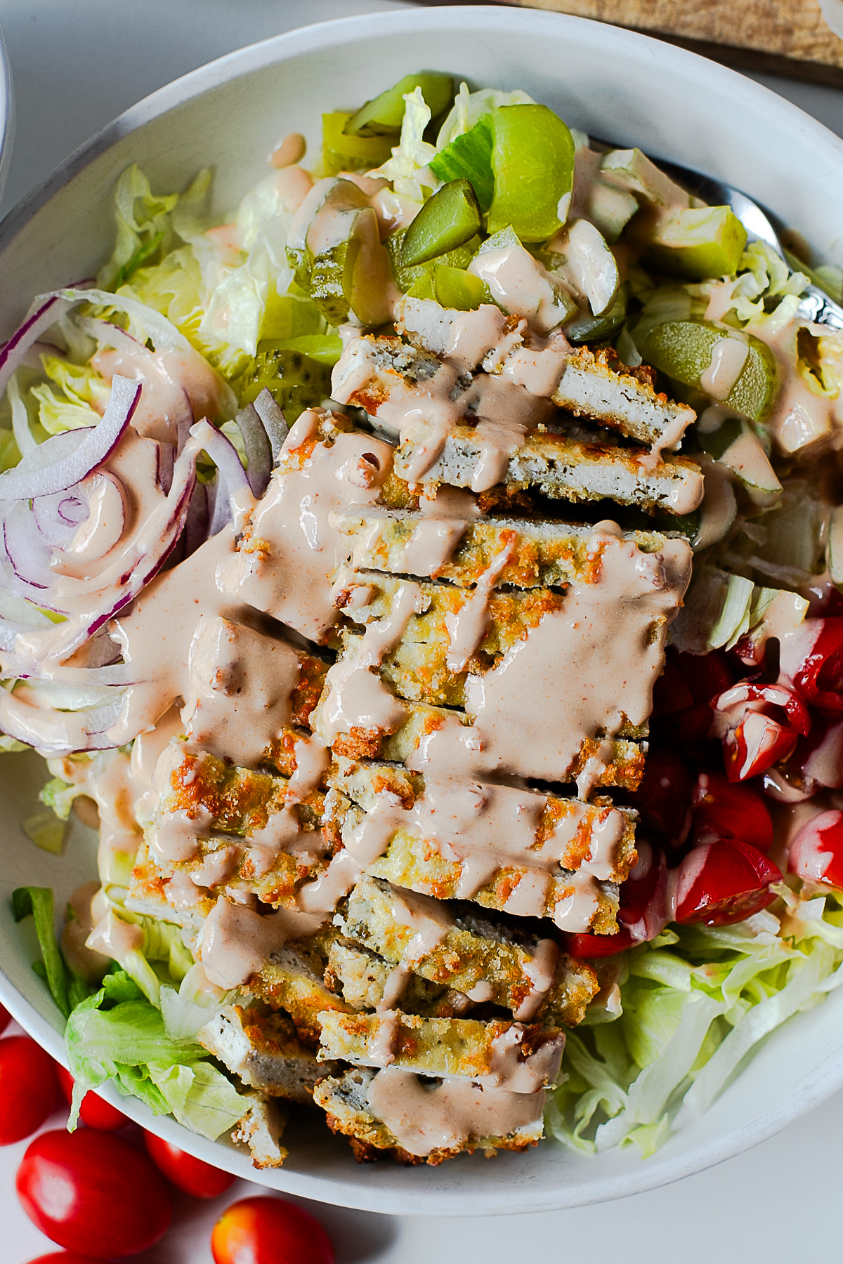 Close-up of crispy chicken cutlet bowl smothered in creamy burger sauce