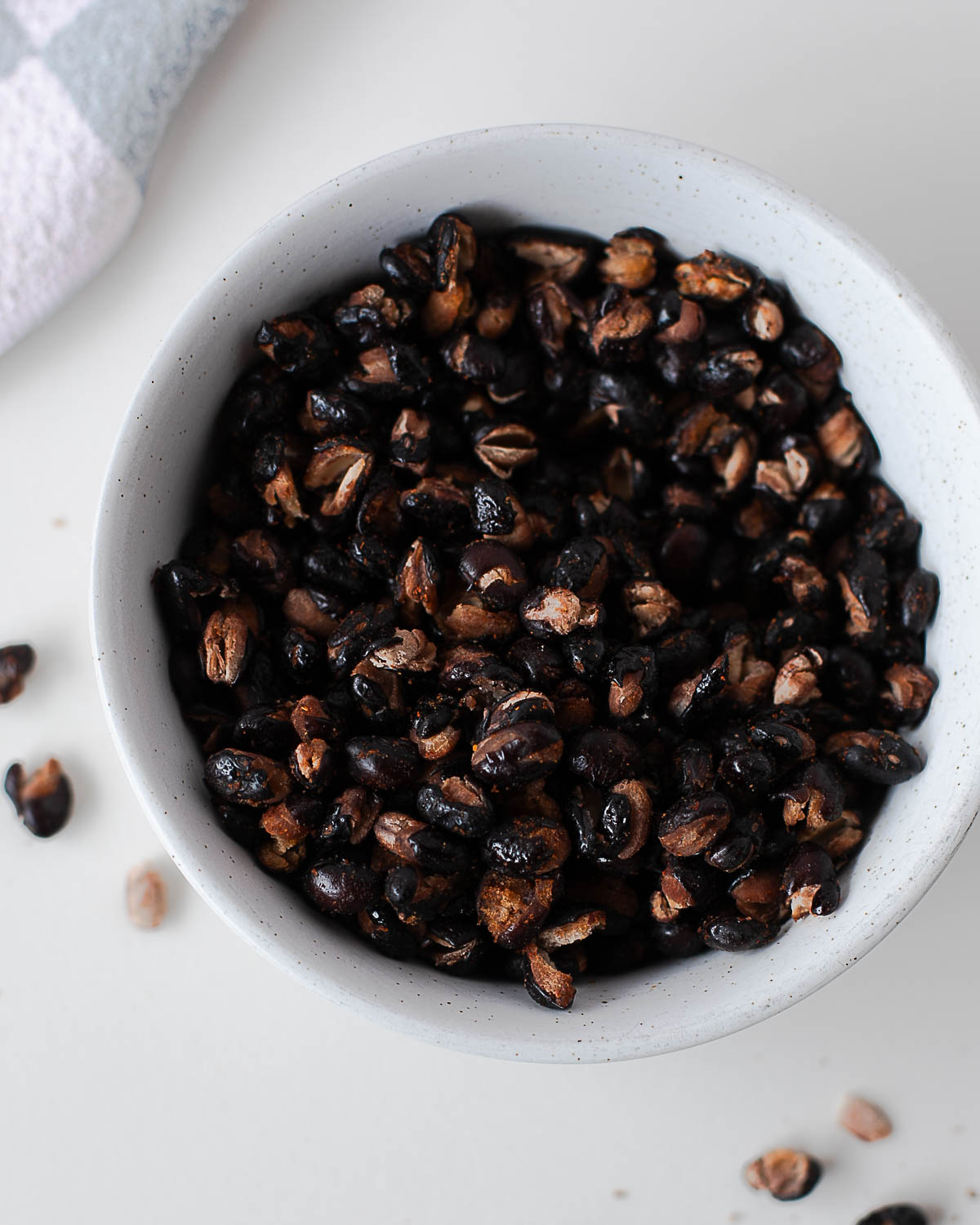 Close-up overhead shot of crispy roasted black beans piled in a small ceramic bowl.