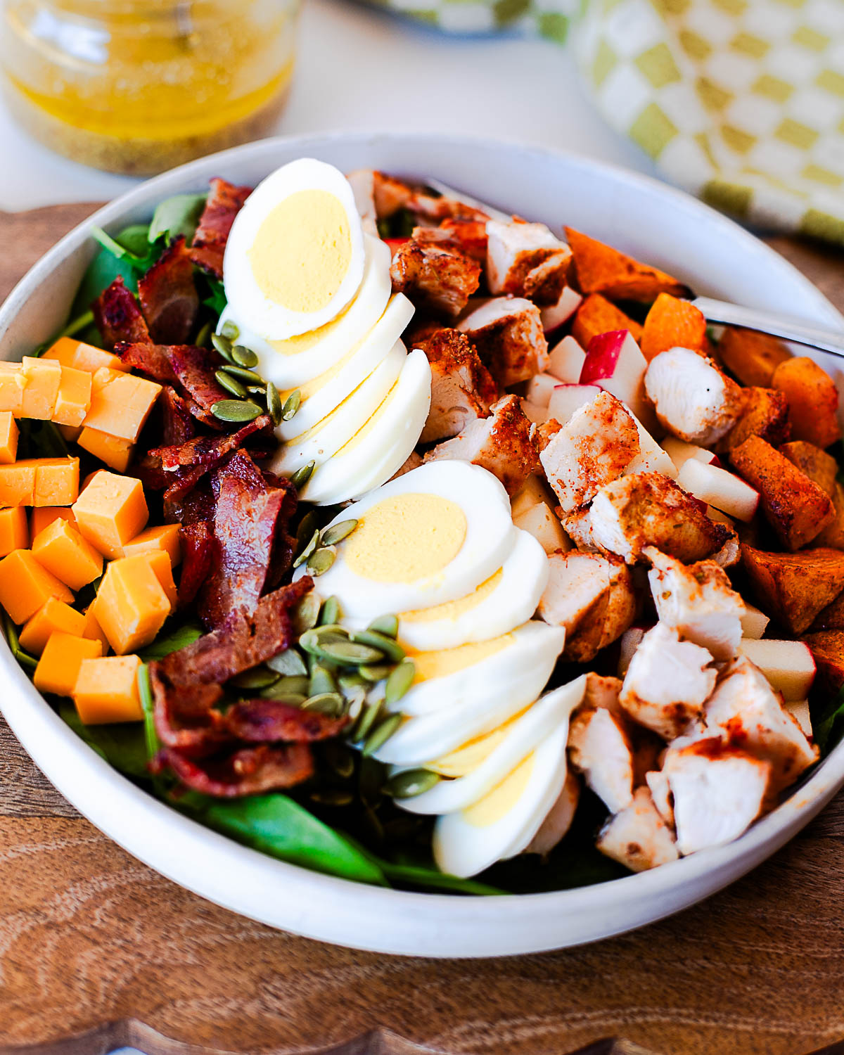 Angled shot of harvest cobb salad in a white bowl with a fork resting on the side