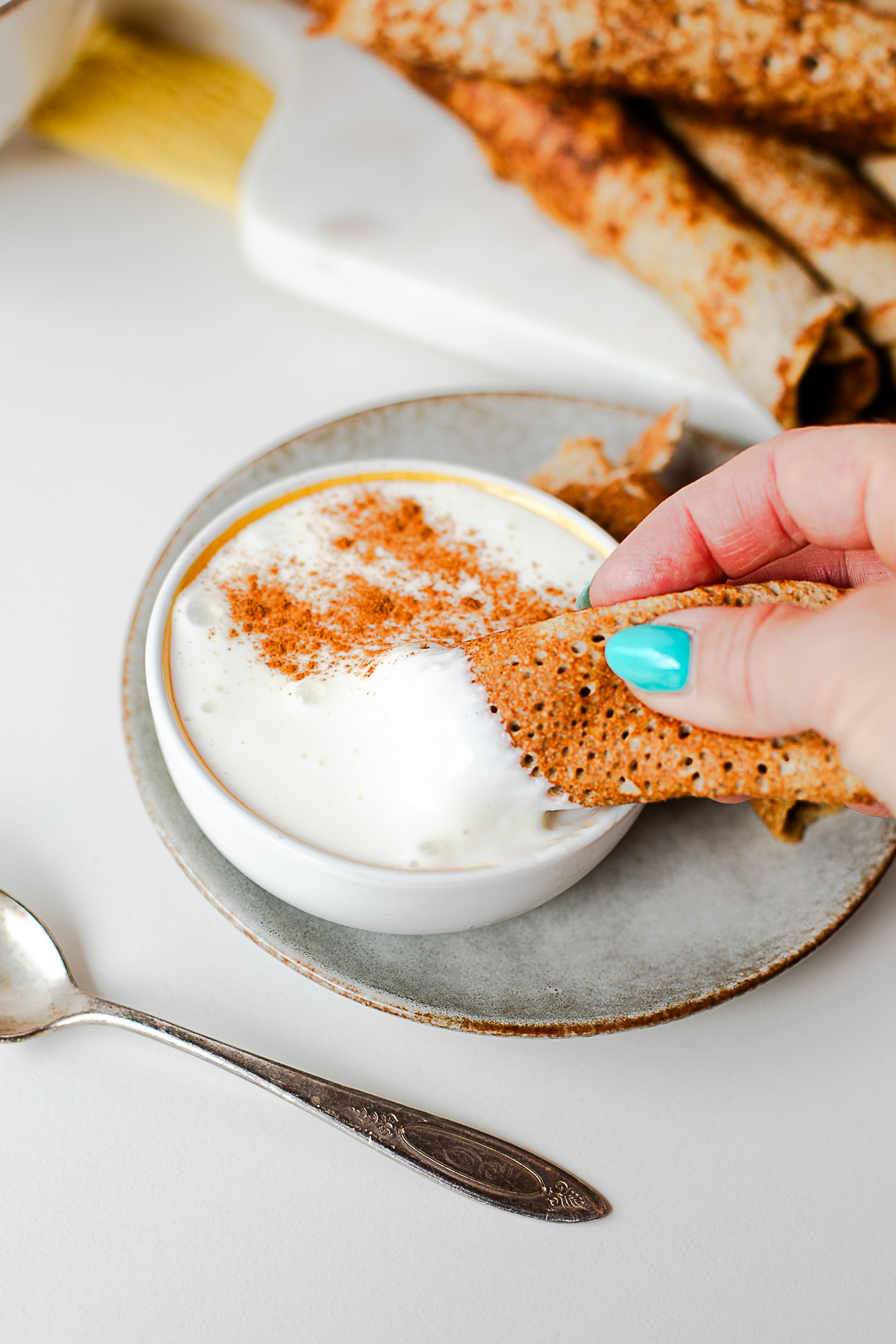 Hand dipping a sliced apple crepe into cottage cheese honey dip