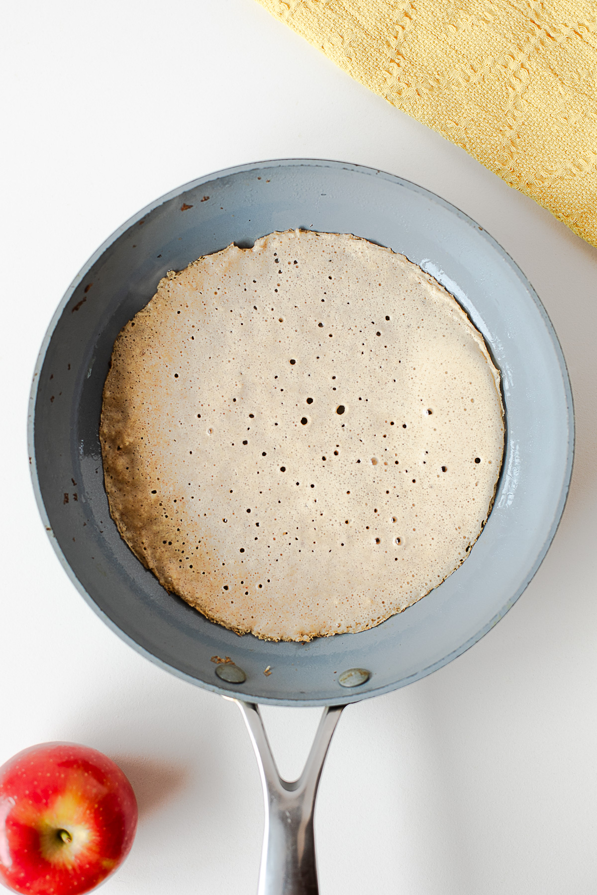 Thin apple crepe cooking in a nonstick skillet
