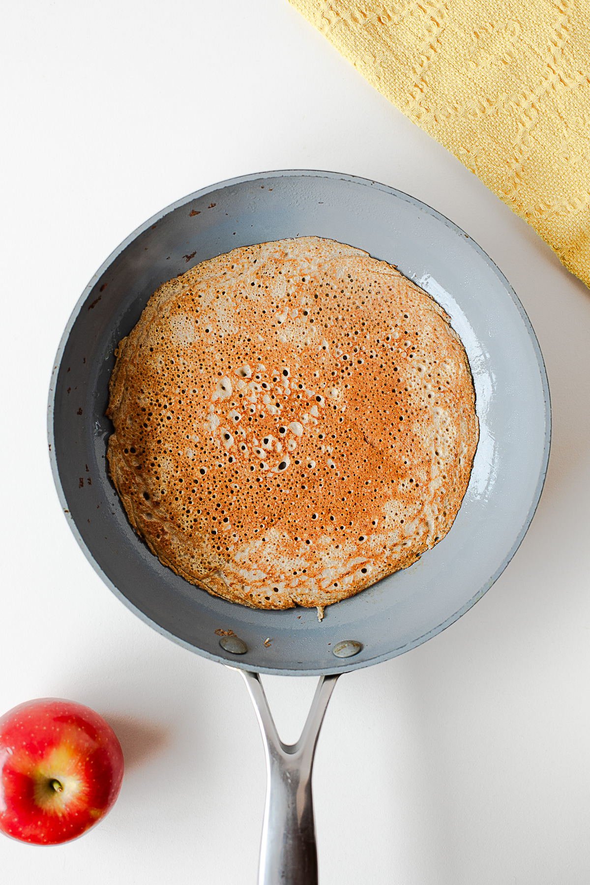 Golden brown apple cinnamon crepe flipped in a skillet