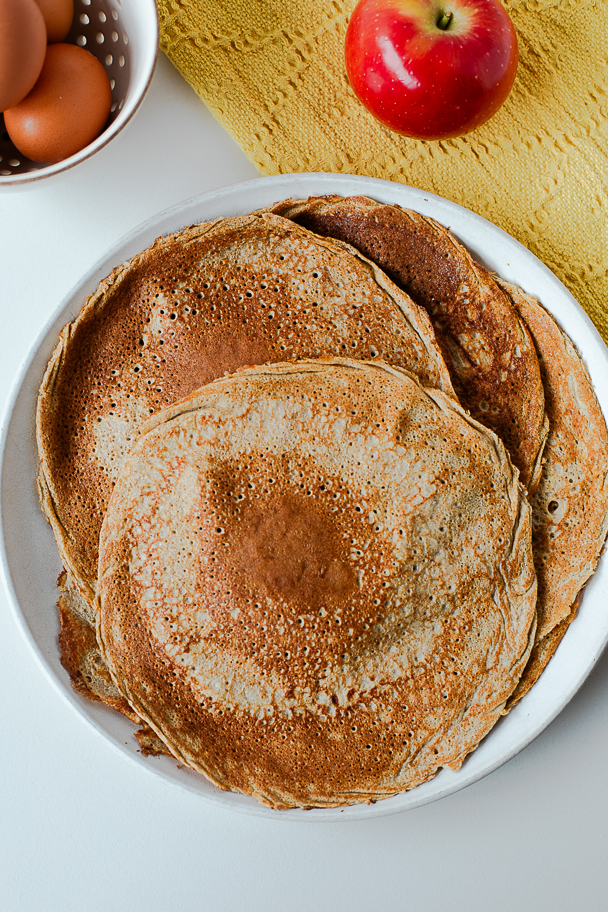 Stack of cooked apple crepes on a plate ready for meal prep