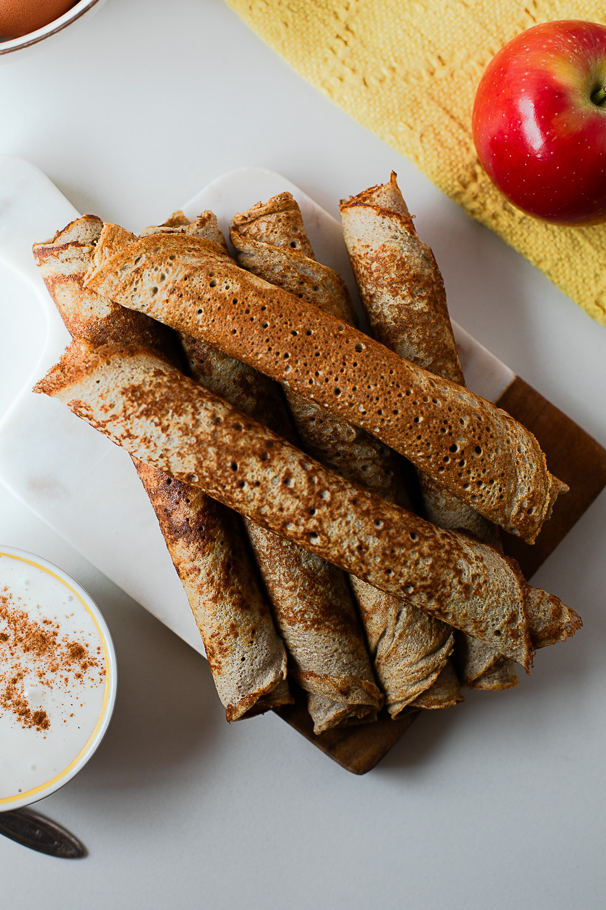 Rolled apple cinnamon crepes on a wooden board