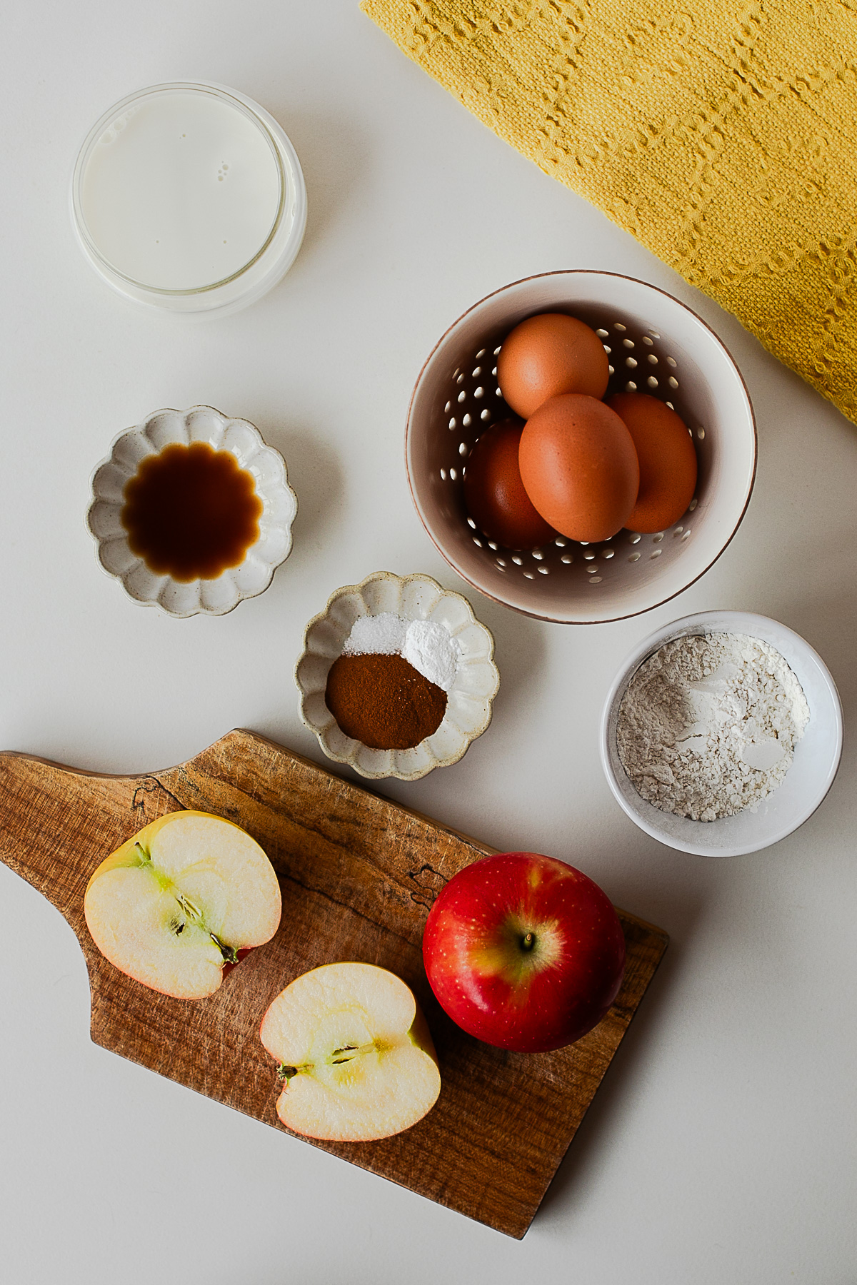 Ingredients for apple crepes, including eggs, milk, vanilla, whole wheat flour, cinnamon, a diced apple, cottage cheese and cream cheese