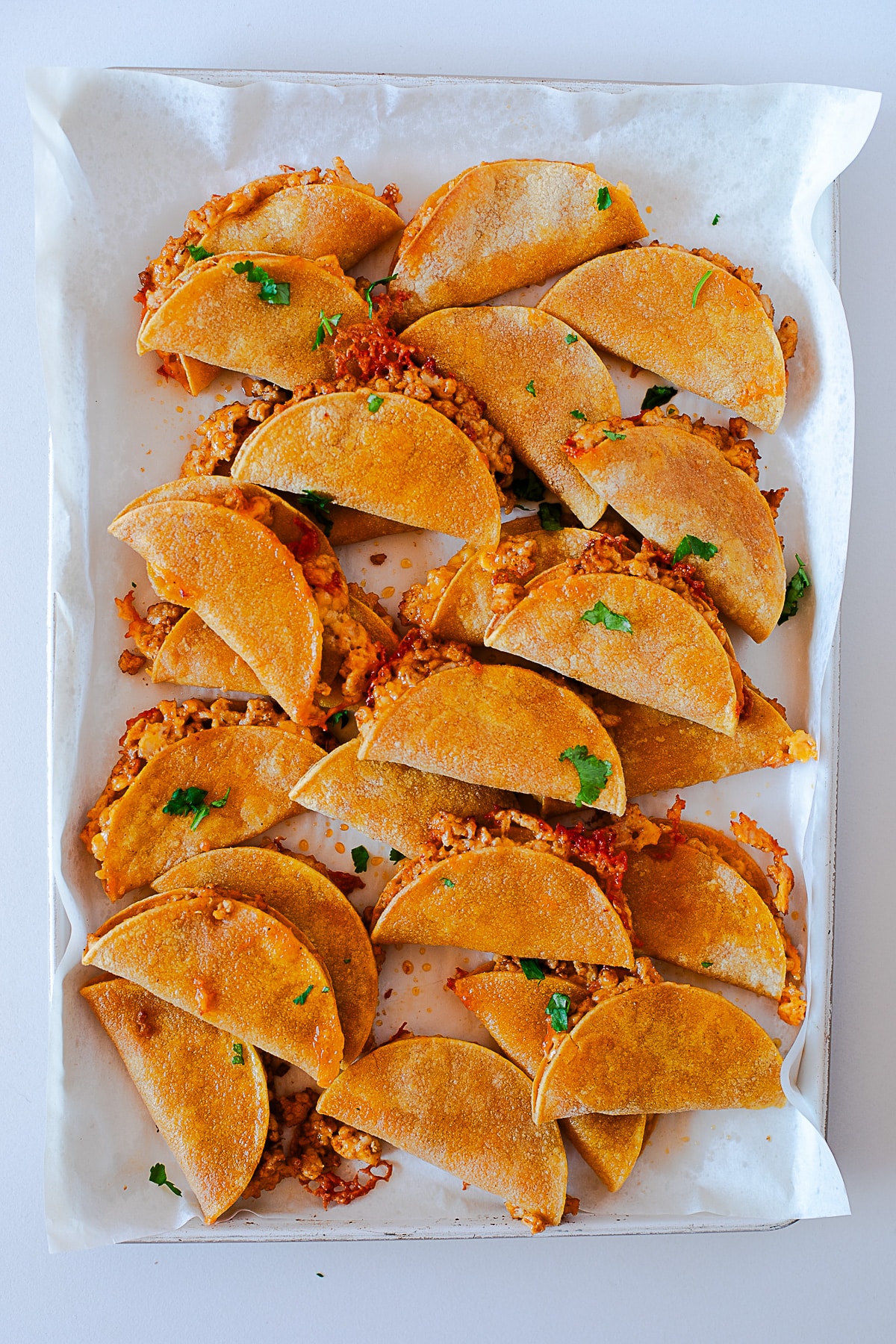 Sheet pan of baked chicken tacos sprinkled with fresh cilantro