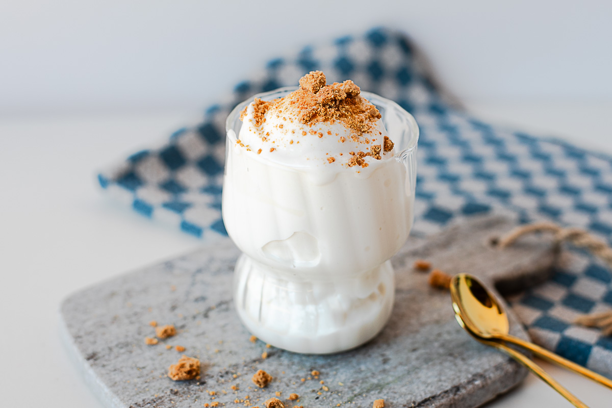 Close-up side view of creamy protein ice cream in glass cup with a spoon.