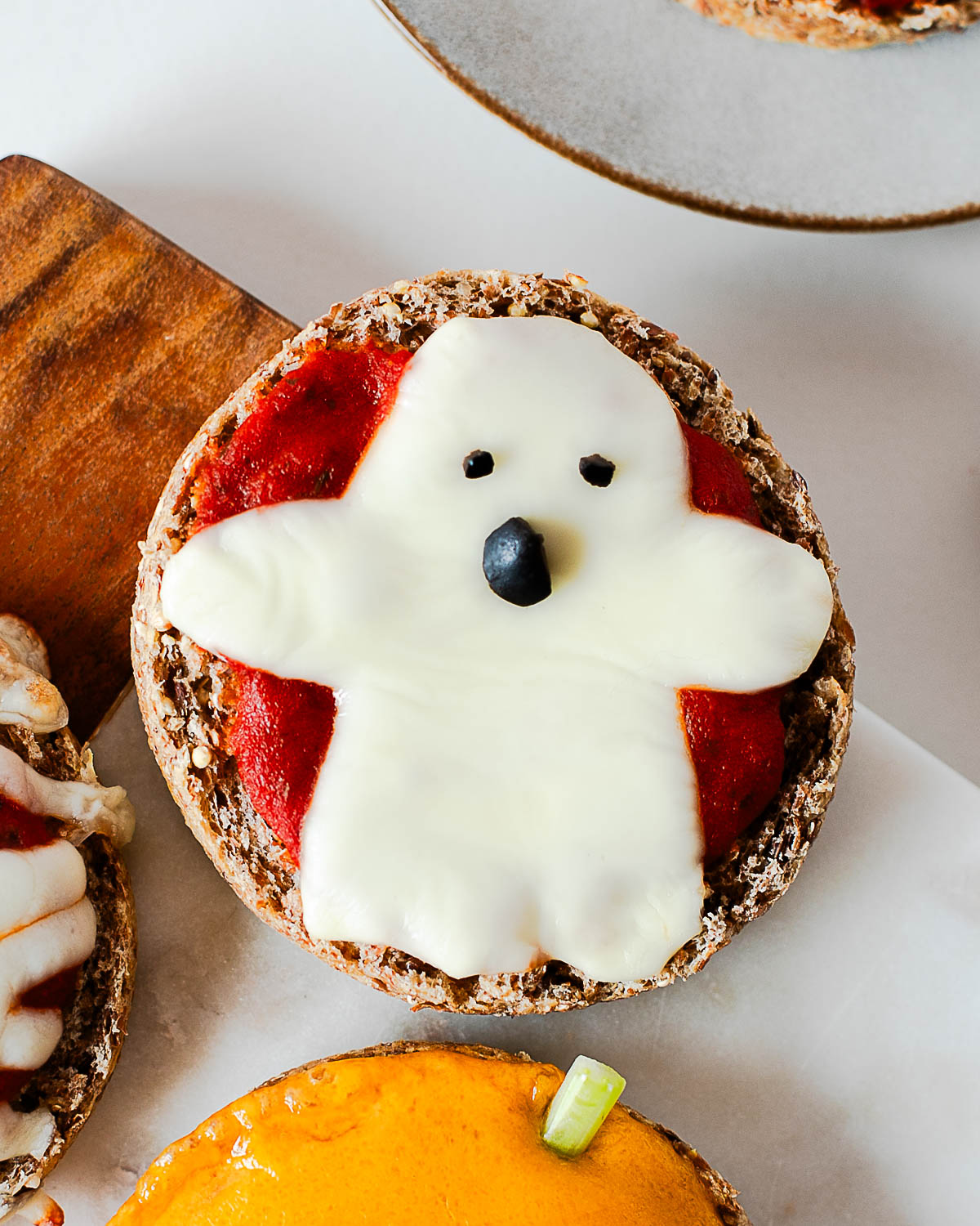 Close-up of a ghost Halloween mini pizza made with mozzarella cheese and olive eyes and nose.