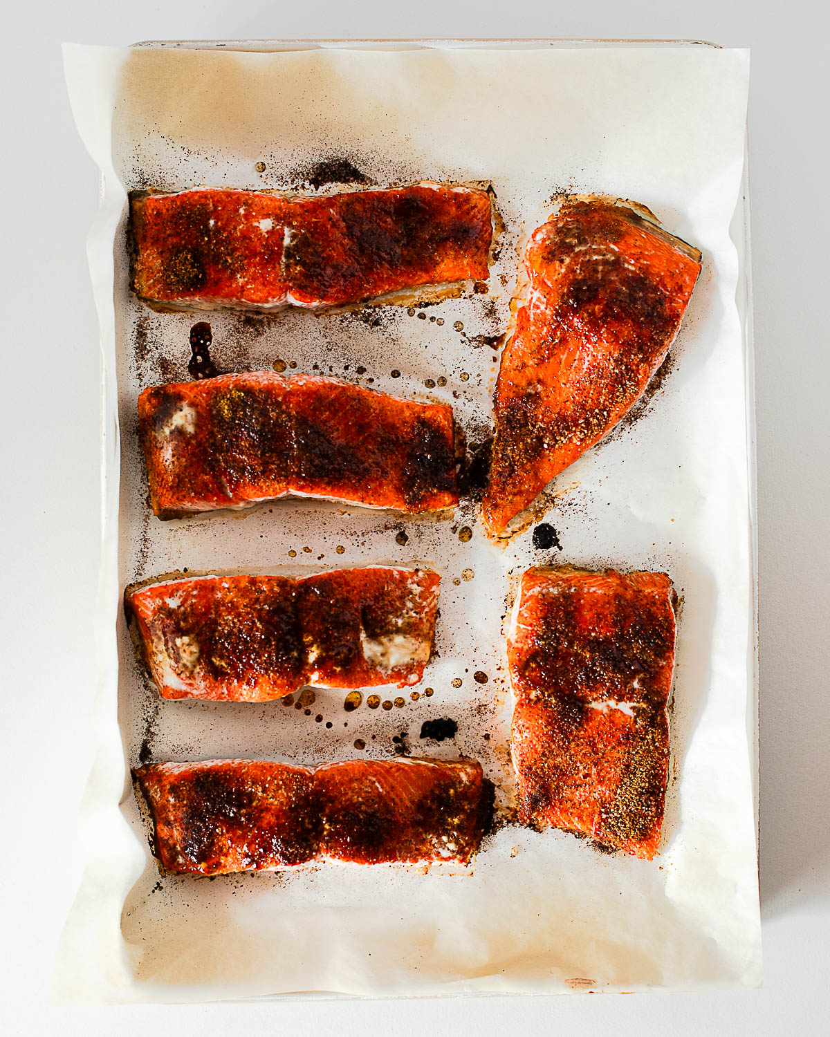 Baked hot honey salmon fillets on a parchment lined baking sheet, caramelized and cooked through