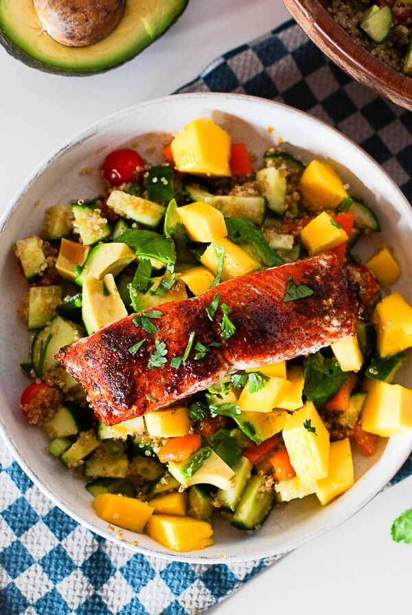 Overhead shot of a hot honey salmon bowl topped with mango, avocado and fresh cilantro