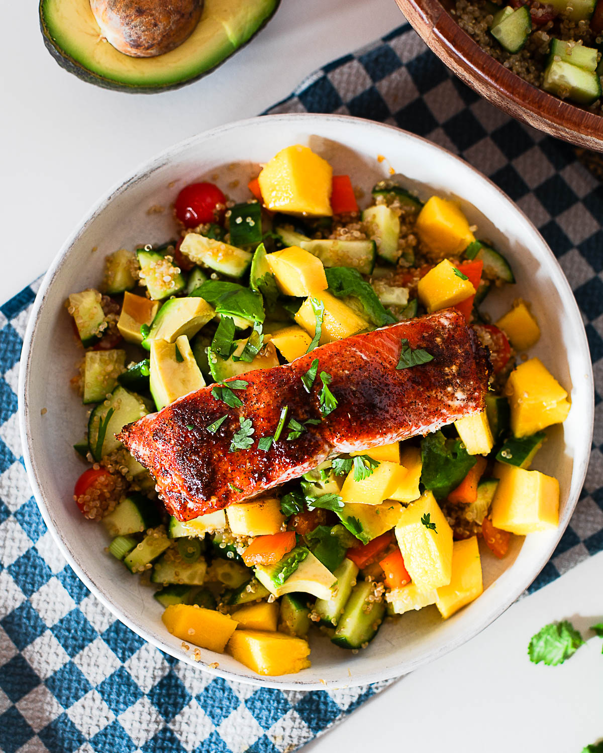 Overhead shot of a hot honey salmon bowl topped with mango, avocado and fresh cilantro