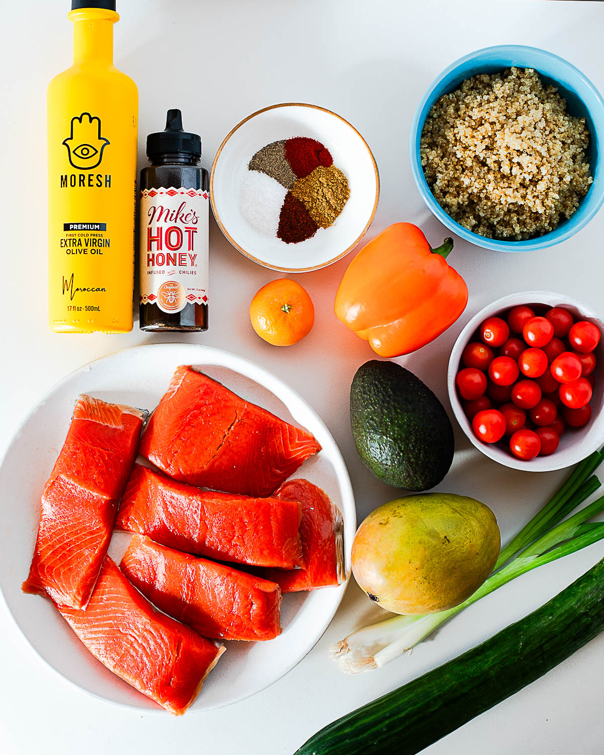 ngredients for hot honey salmon bowls, including salmon, quinoa, mango, avocado, bell pepper, cherry tomatoes and hot honey