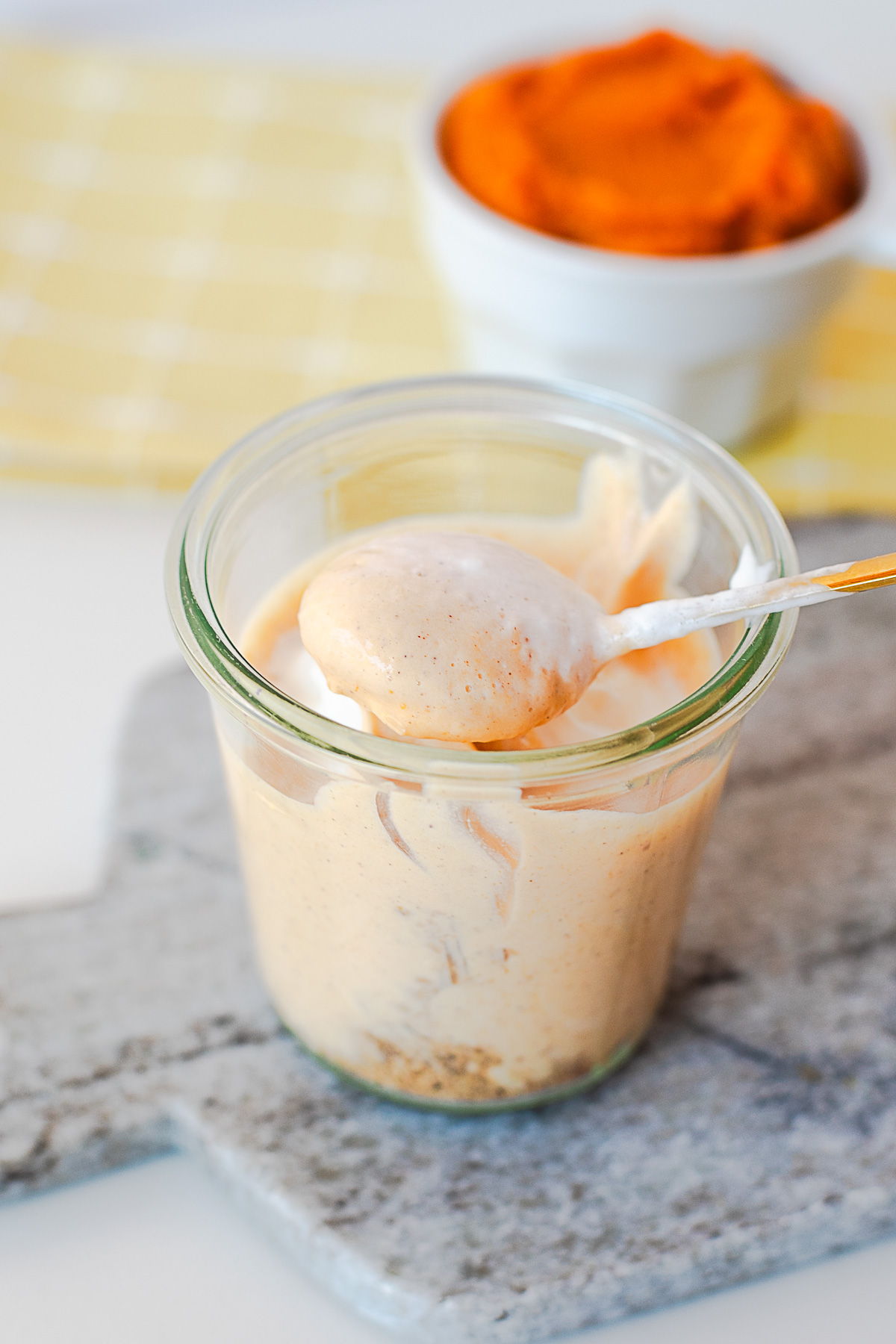 Spoon scooping creamy pumpkin pie yogurt out of a glass jar