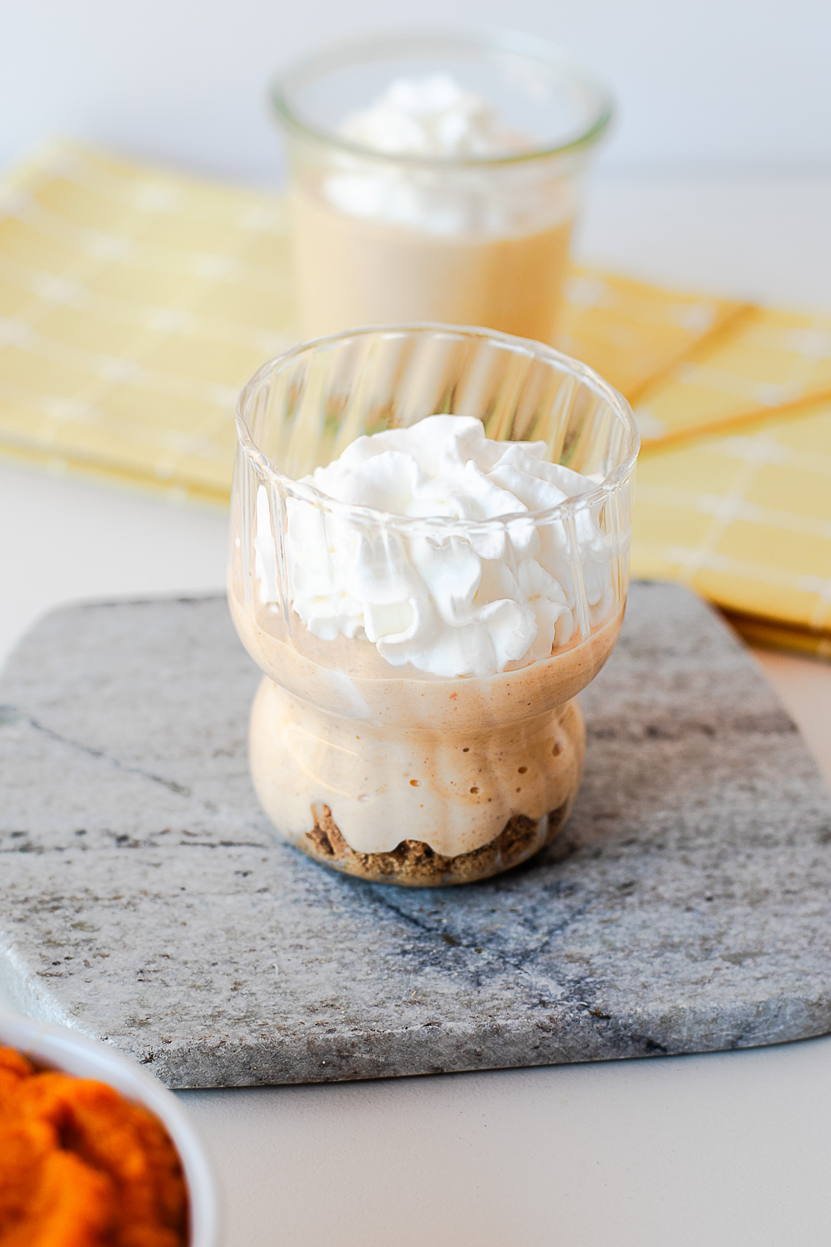 Two jars of high protein pumpkin pie yogurt with a crushed cookie crust and whipped cream