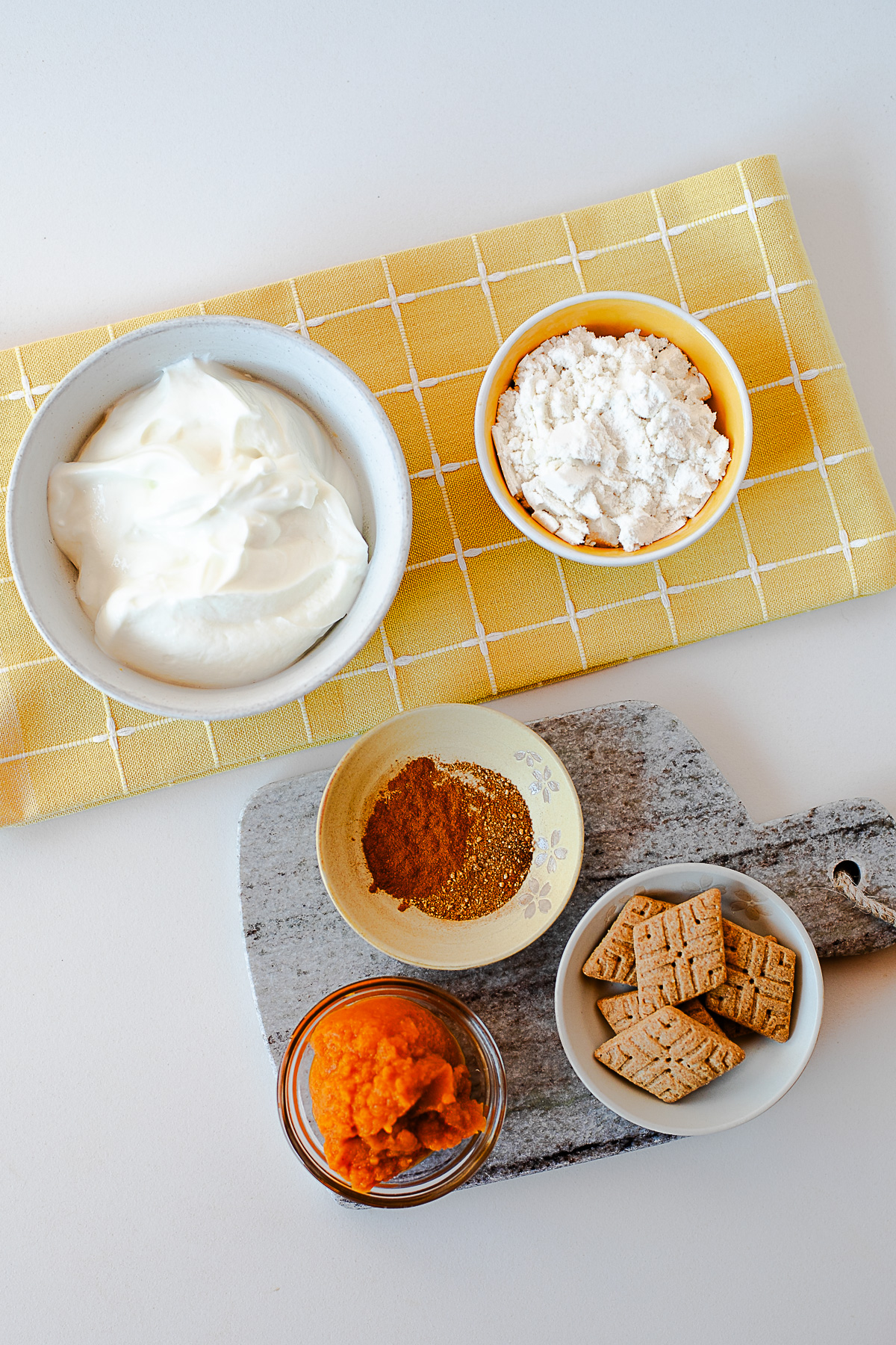 Ingredients for pumpkin pie yogurt, including Greek yogurt, vanilla protein powder, pumpkin puree, pumpkin pie spice and Simple Mills Sweet Thins
