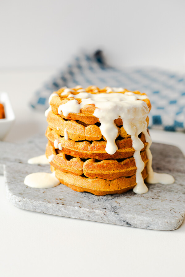 Stack of pumpkin protein waffles topped with a creamy honey cottage cheese drizzle