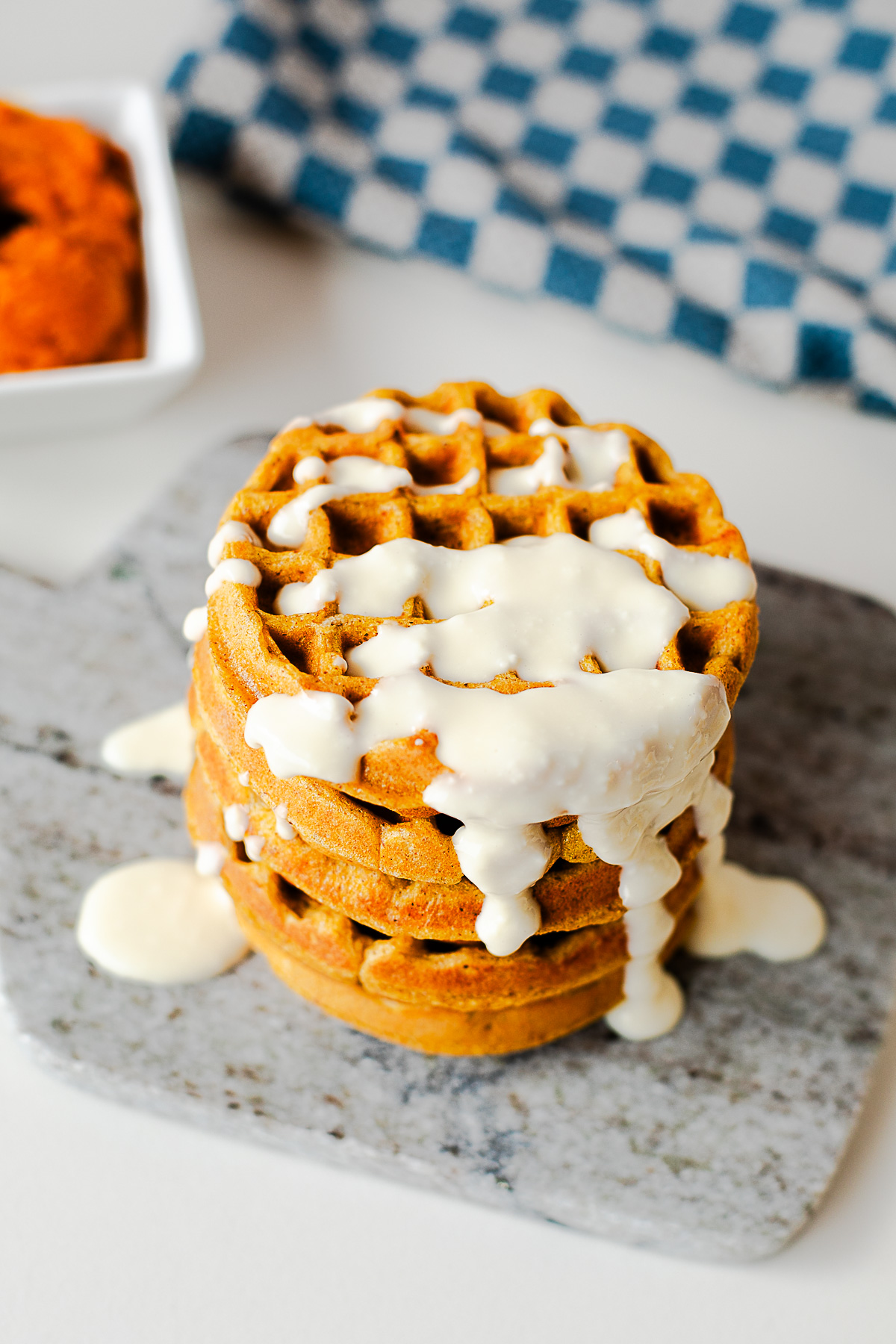 Close-up of a stack of pumpkin protein waffles drizzled with honey cottage cheese